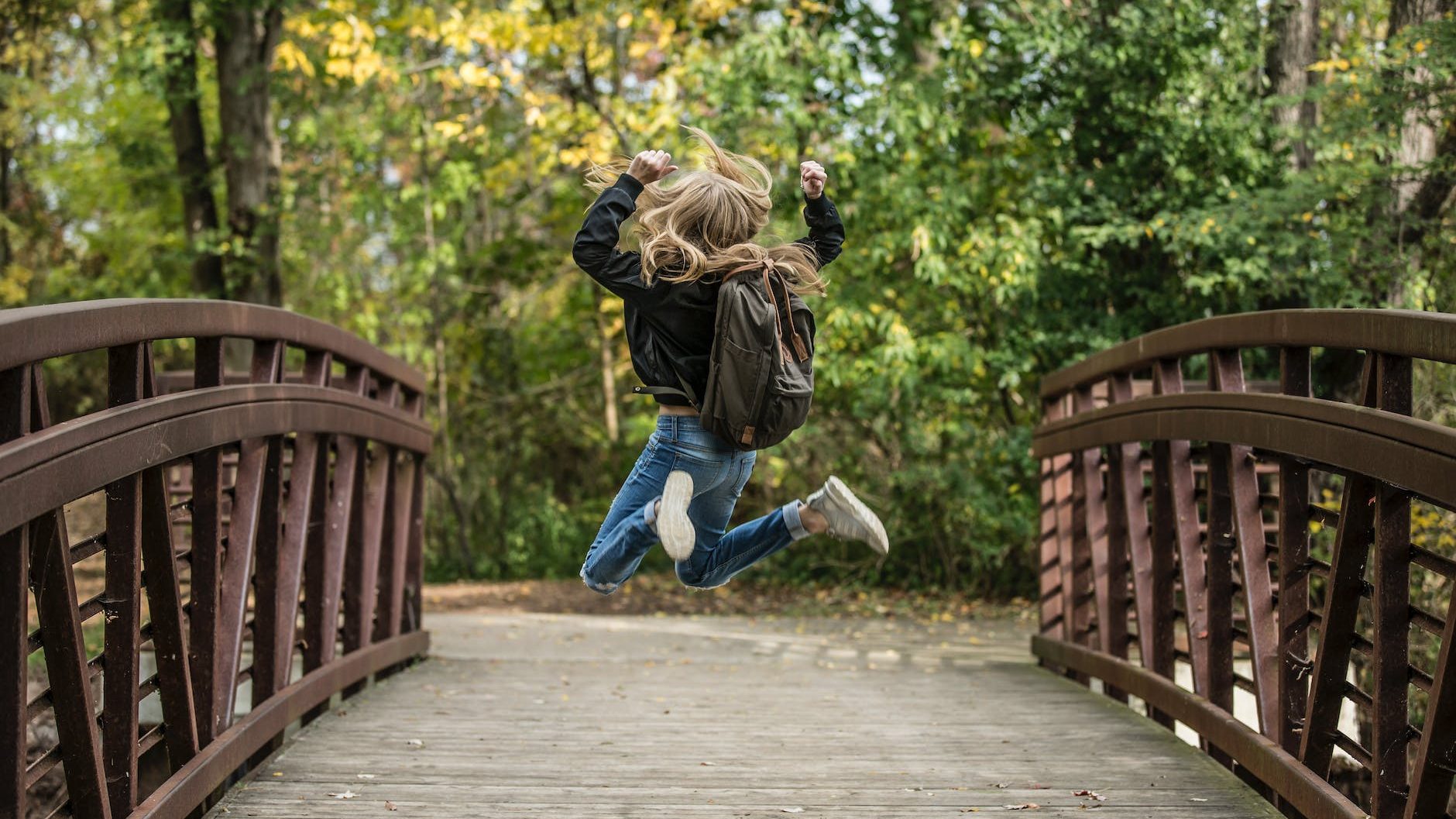 girl jumping on the bridge wearing black jacket